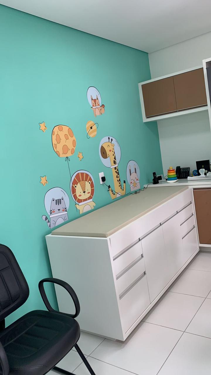 Sala de atendimento infantil com decoração lúdica de animais astronautas